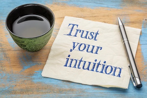 Tasse de thé avec papier et crayon et écrit "Trust your intuition"